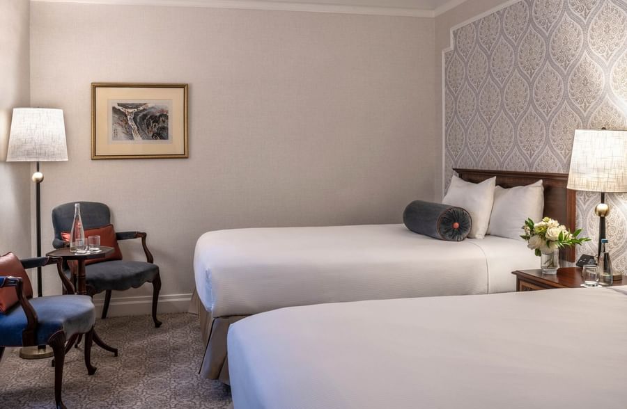 Two beds with pillows and a small table with flowers in a room at Warwick New York.