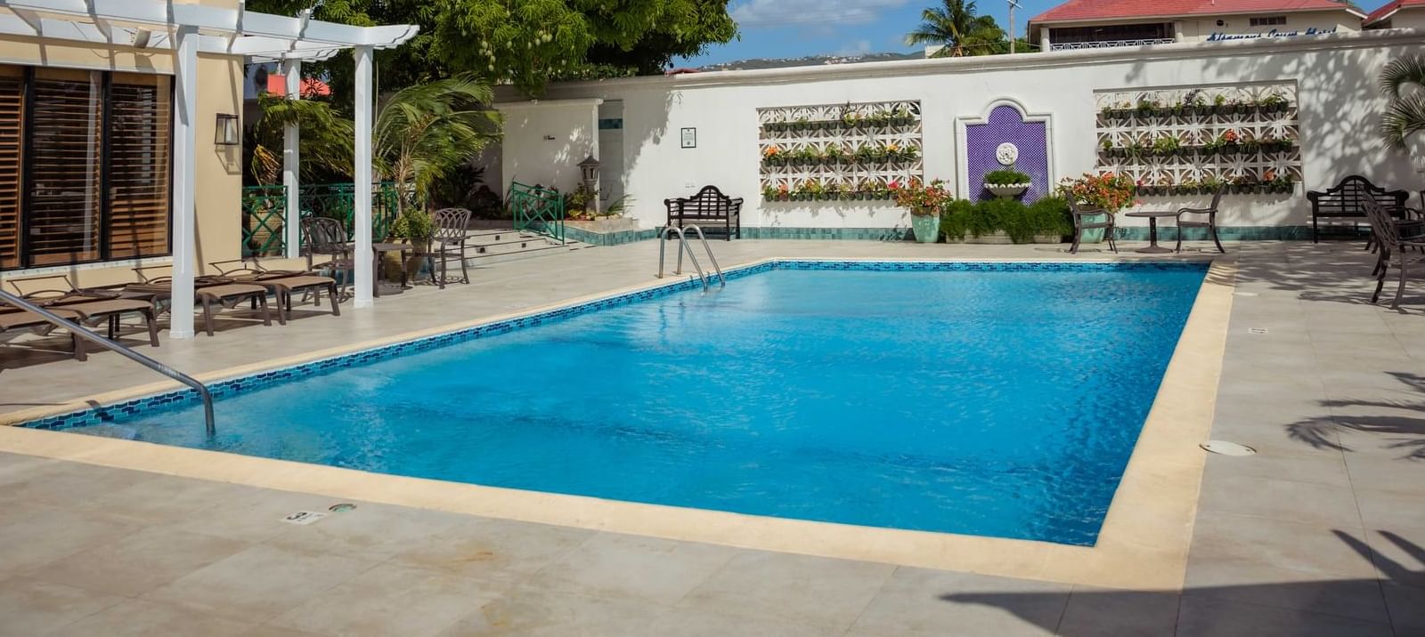 Sunbeds and chairs arranged by the hotel outdoor pool at Courtleigh Hotel & Suites