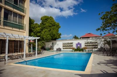 Sunbeds and chairs arranged by the hotel outdoor pool at Courtleigh Hotel & Suites