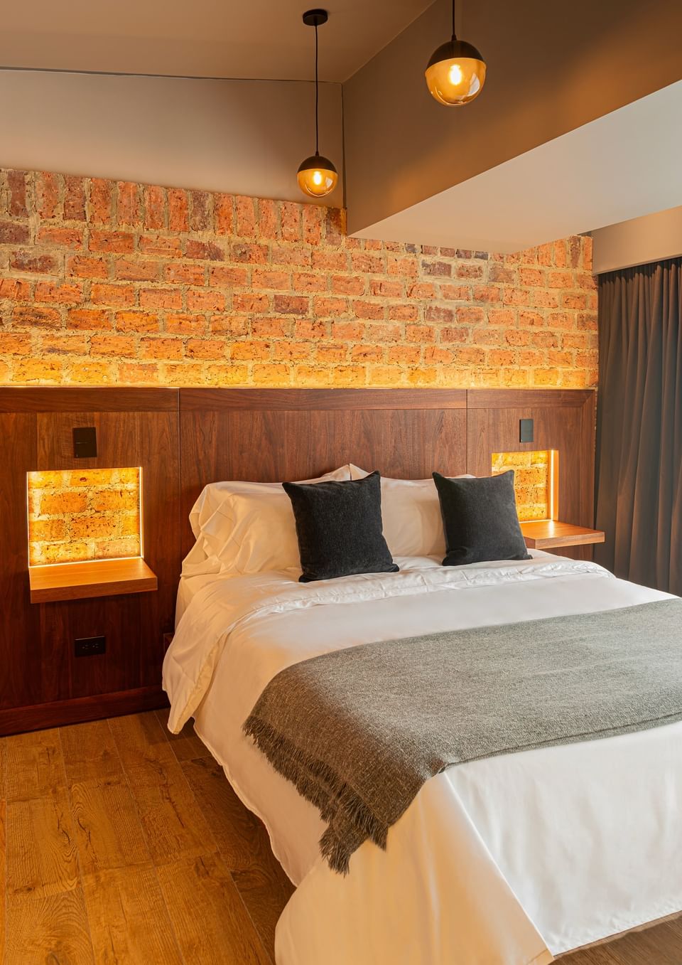 Plush bed by a brick wall, ideal Bogota accommodations in Studio with Balcony room at 5Q House Chapinero