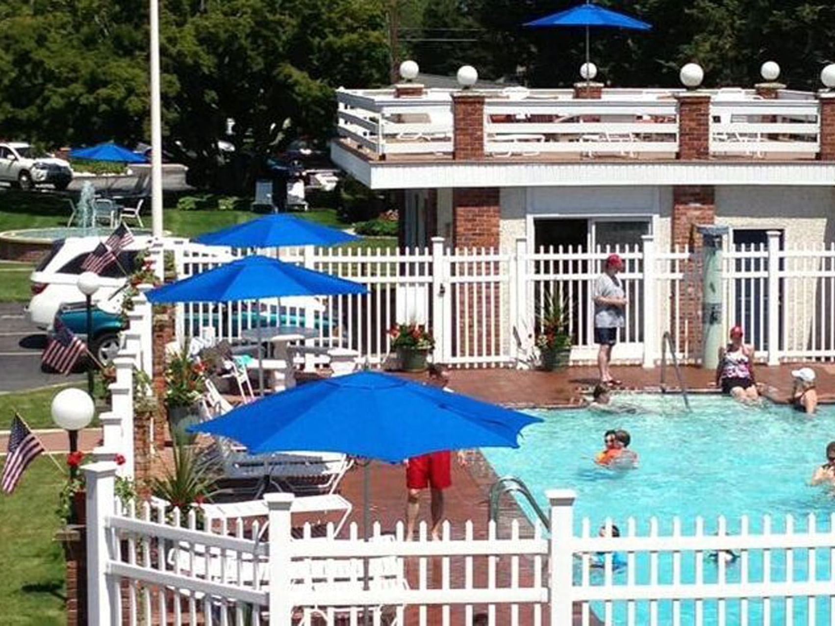 Loungers under umbrellas beside a sunlit pool, with people swimming and enjoying at Breezeway Boutique Hotel