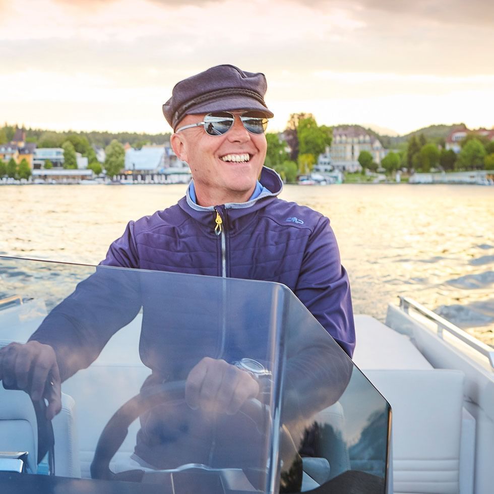 Man sailing a boat in the sea near Falkensteiner Schlosshotel Velden