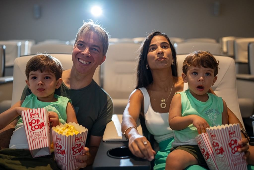 Happy family including two young boys eat popcorn and watch a movie in the comfortable private Hotel X Toronto