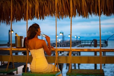 A girl having a cocktail under a thatched tent at Fiesta Resort