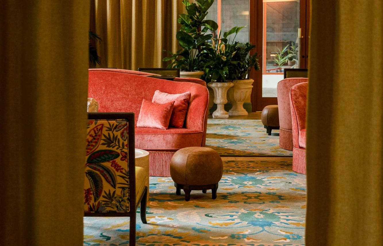 Elegant lounge with red couches, patterned rugs, and a glass door at The 27 Wynwood