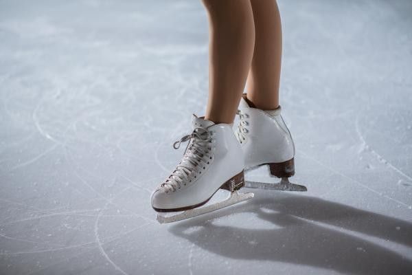 Ice skater wearing white ice skating boots on the rink surface