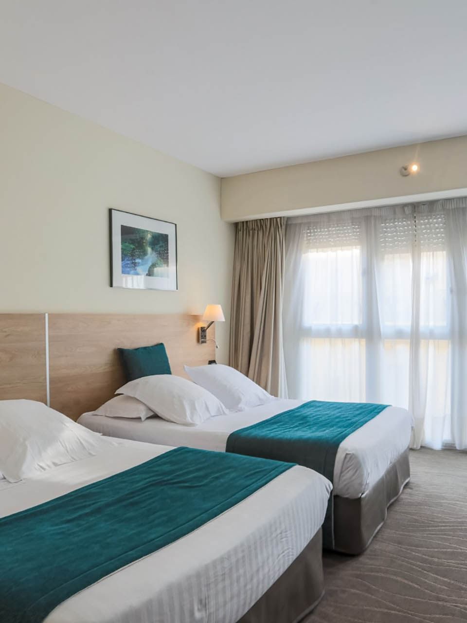 Family Room with two beds, teal accents, a wooden headboard, and chairs near the window at Splendid Hotel & Spa Nice