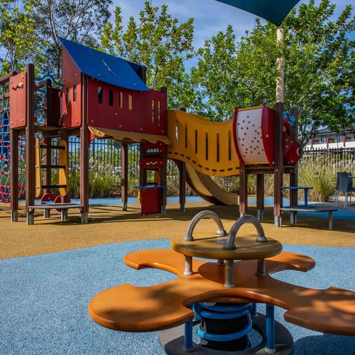 Colorful playground with a slide, climbing structures, and a roundabout at Mercure Kooindah Waters