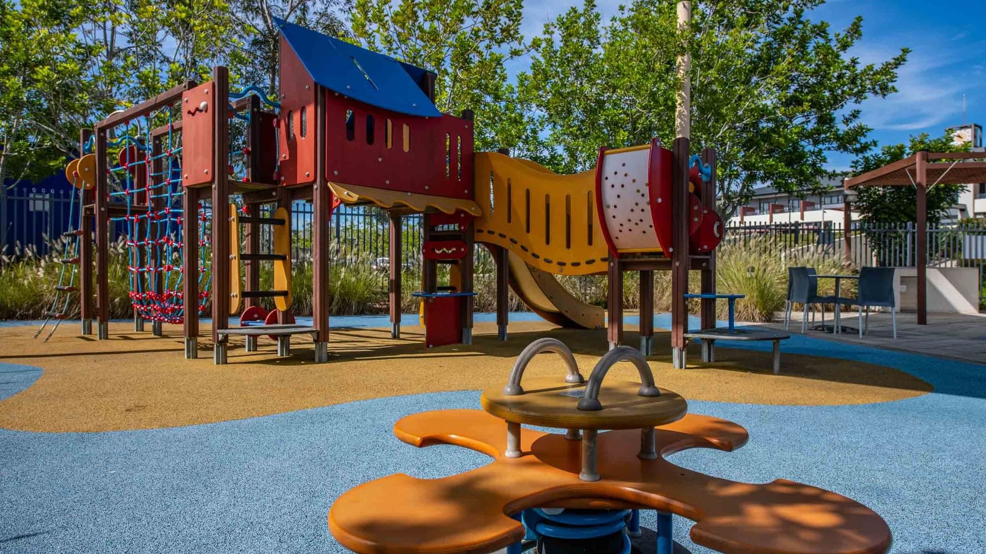 Colorful playground with a slide, climbing structures, and a roundabout at Mercure Kooindah Waters