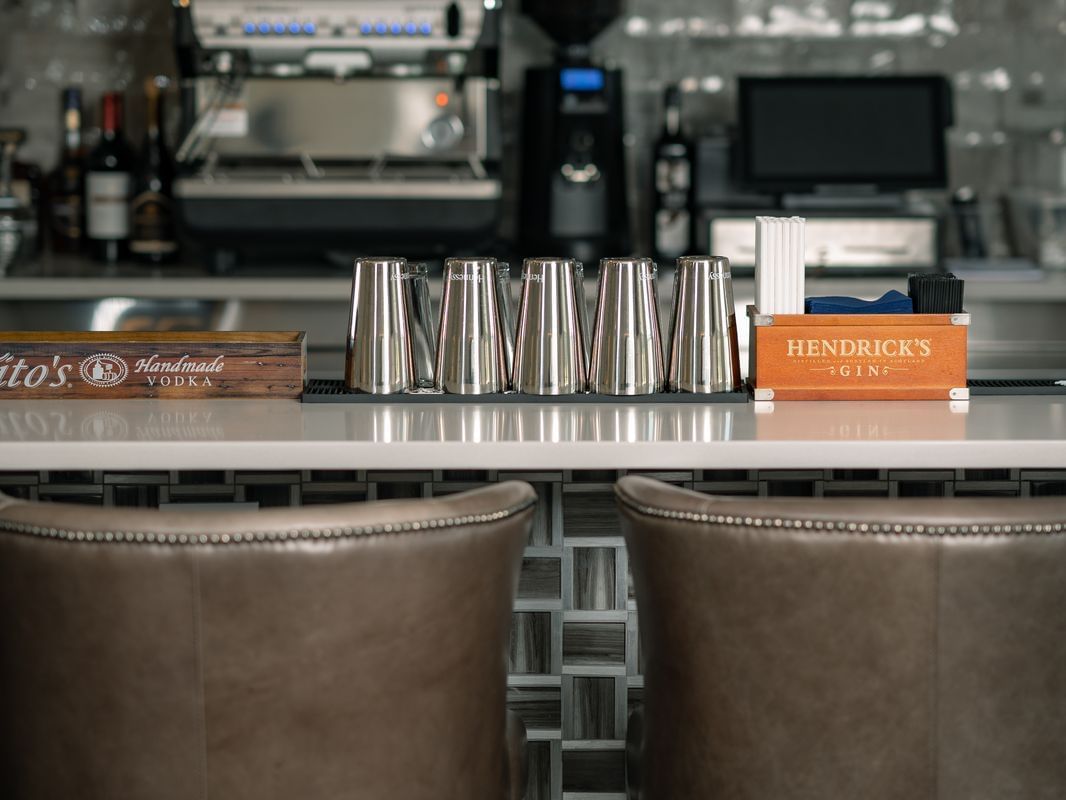 two bar stools and mixing glasses at a bar