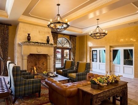 Lorem ipsum Living room with a fireplace, sofa and four chairs. Two chandeliers are hanging from the ceiling.