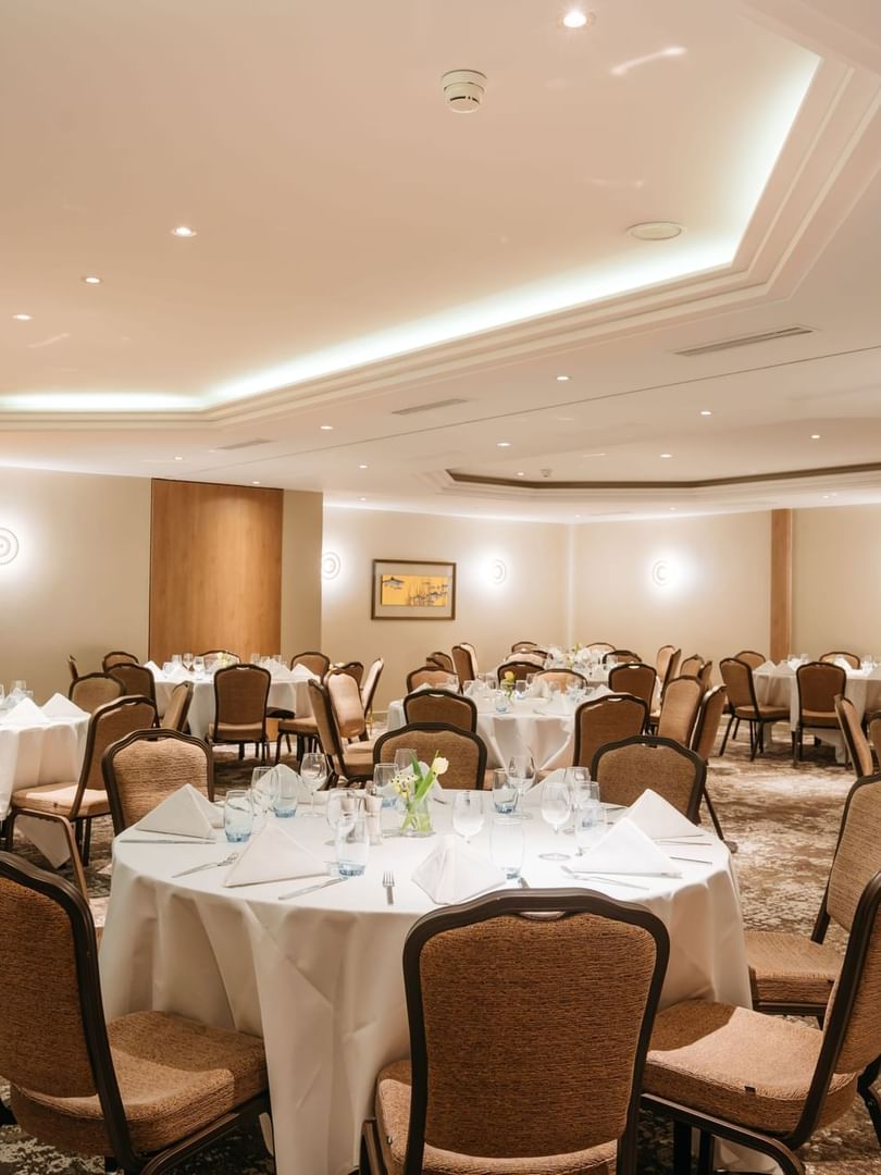 Elegant round tables by tan walls surrounding a patterned carpet in Mont-Rose + Dent-Blanche at Warwick Geneva