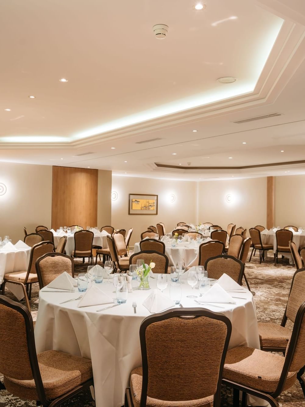 Elegant round tables by tan walls surrounding a patterned carpet in Mont-Rose + Dent-Blanche at Warwick Geneva