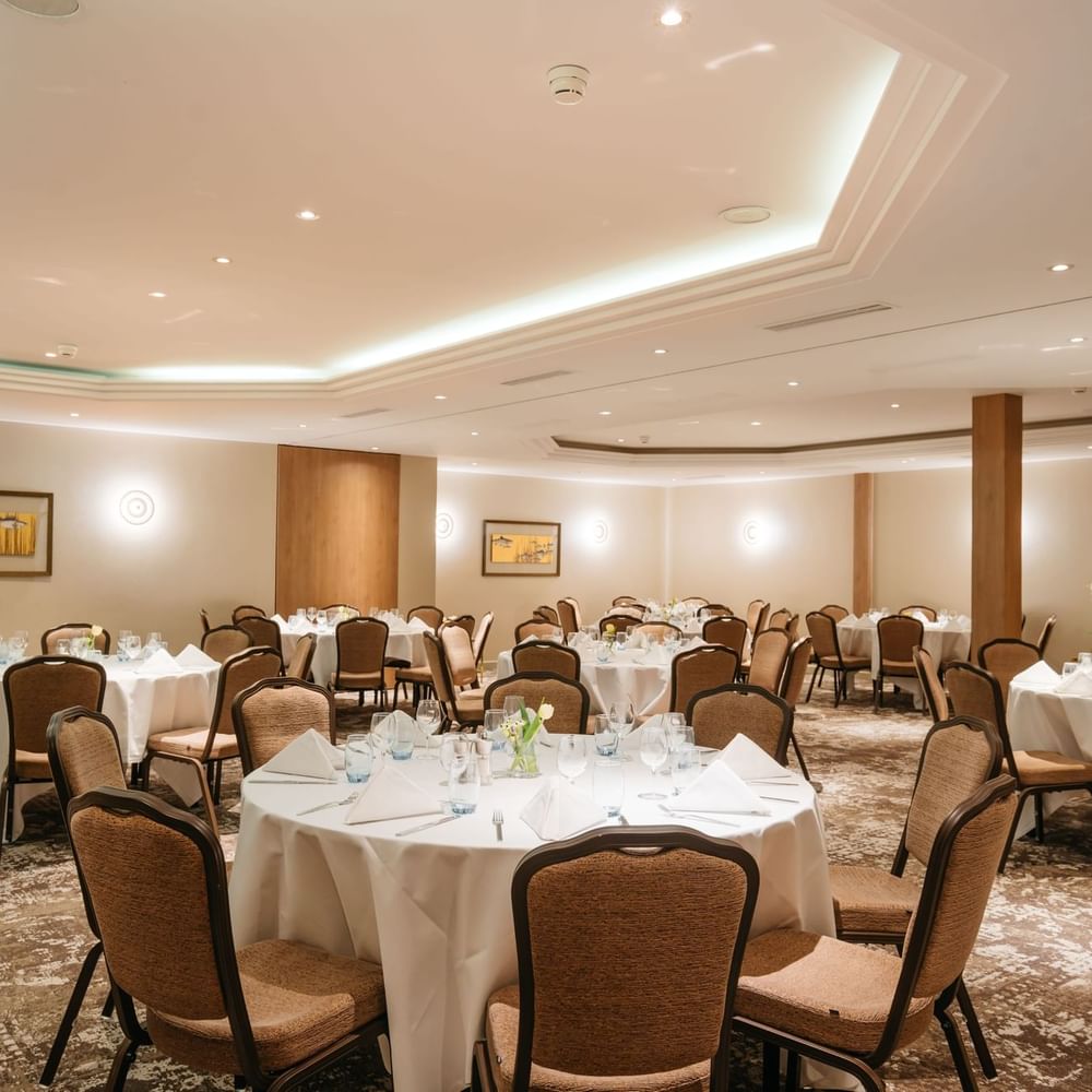 Elegant round tables by tan walls surrounding a patterned carpet in Mont-Rose + Dent-Blanche at Warwick Geneva