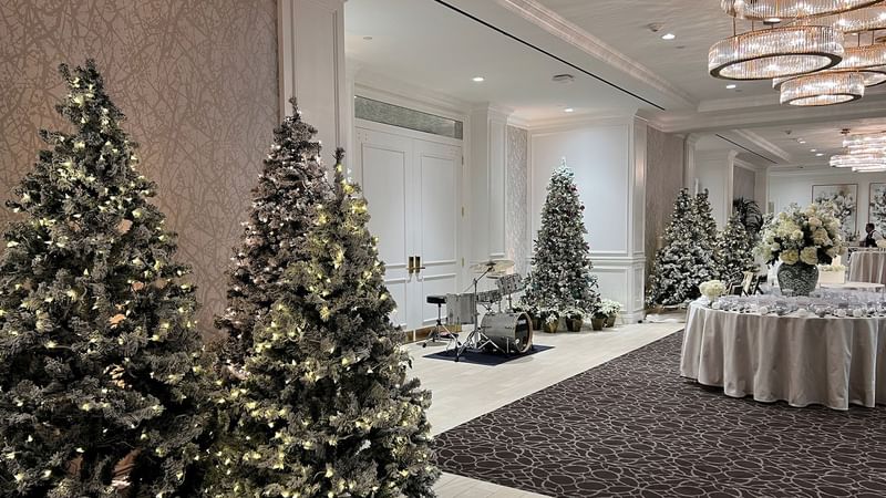 Hall decorated with Christmas trees, a drum set, and floral arrangements featuring Christmas pano at Warwick Melrose Dallas