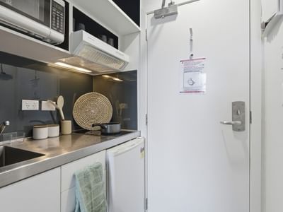 A kitchen with a sink, microwave, and refrigerator at UniLodge Auckland City.