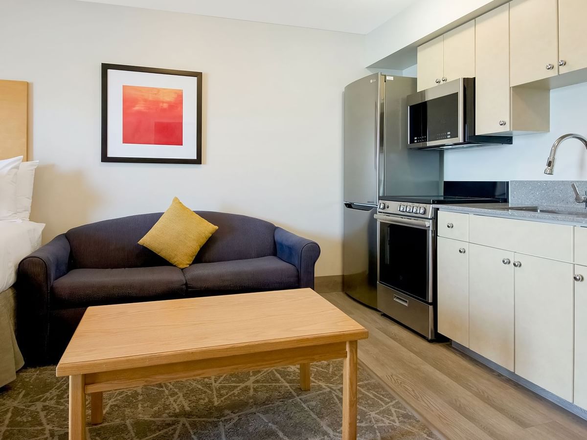 Well-furnished hotel suite with a kitchenette, queen bed and comfortable sofa for a homely stay.