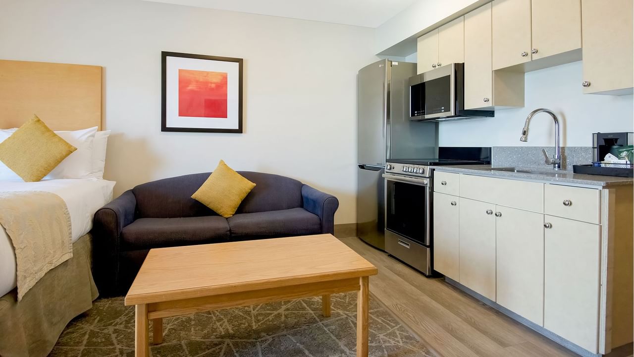 Well-furnished hotel suite with a kitchenette, queen bed and comfortable sofa for a homely stay.