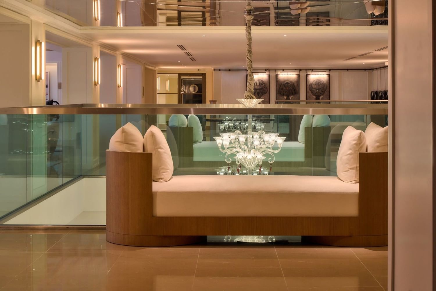 Glass-walled lounge with cushioned bench and chandelier at The May Fair Hotel, London
