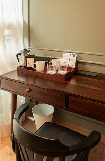 Coffee tray and mugs on dark wood desk by Black chair in one of the Bogota accommodations at 5Q House Chapinero