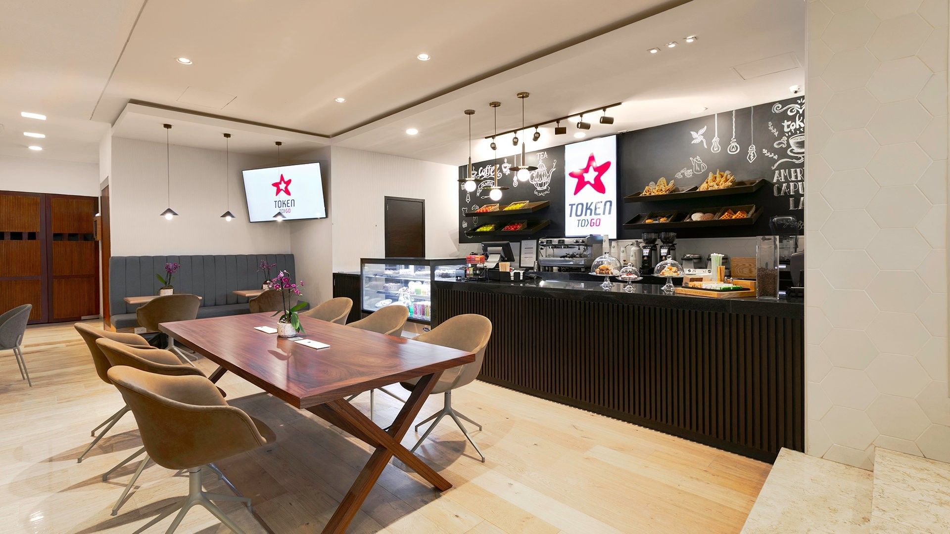 Mesa de comedor de madera con sillas beige cerca del mostrador del café en Camino Real Aeropuerto México