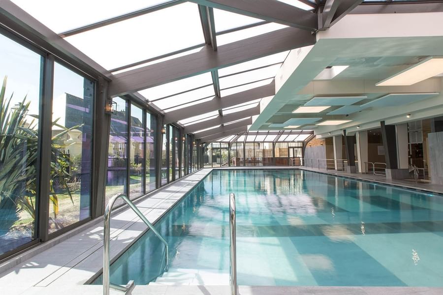 Swimming pool housed under a modern glass and timber roof structure at Le Grand Hôtel des Thermes