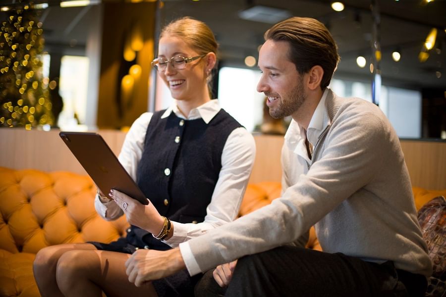 Gäster i lounge på Hotel Riverton diskuterar och arbetar tillsammans i en elegant miljö.