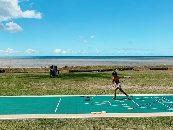 A kid playing shuffle board
