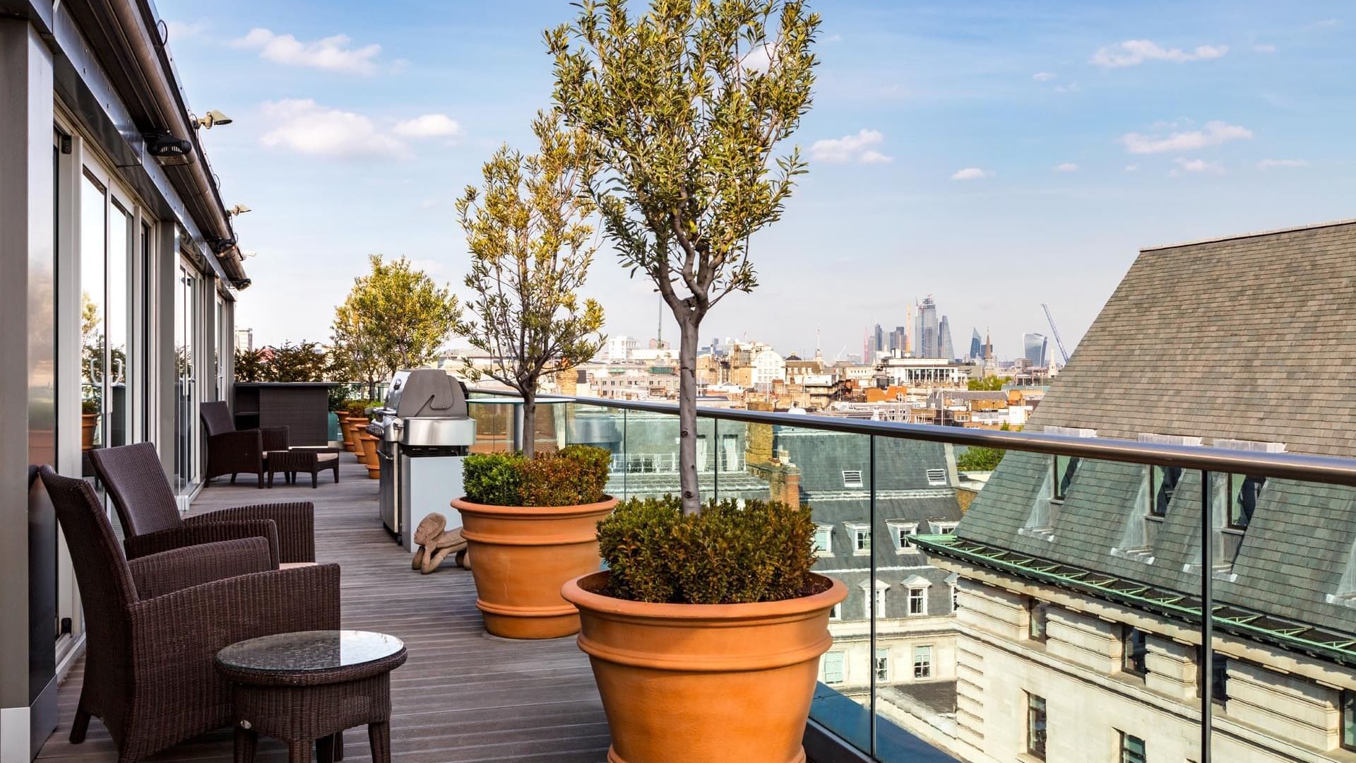 Spacious rooftop terrace in the Penthouse Suite at The May Fair Hotel London, featuring wicker chairs overlooking the city