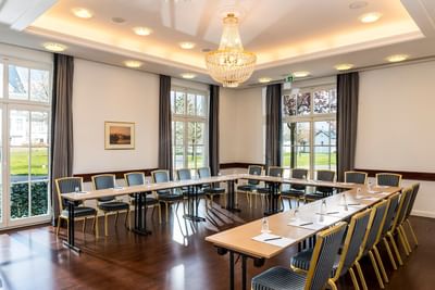 Large conference room with tables and chairs, a chandelier, and large windows with outdoor views.