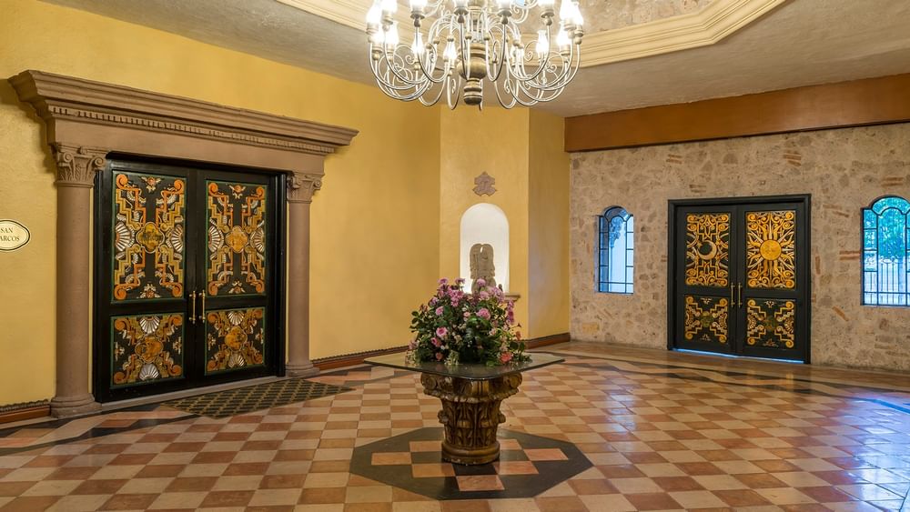 Foyer, Ornate carved doors, and checkered tile floors with a central floral display at Quinta Real Aguascalientes