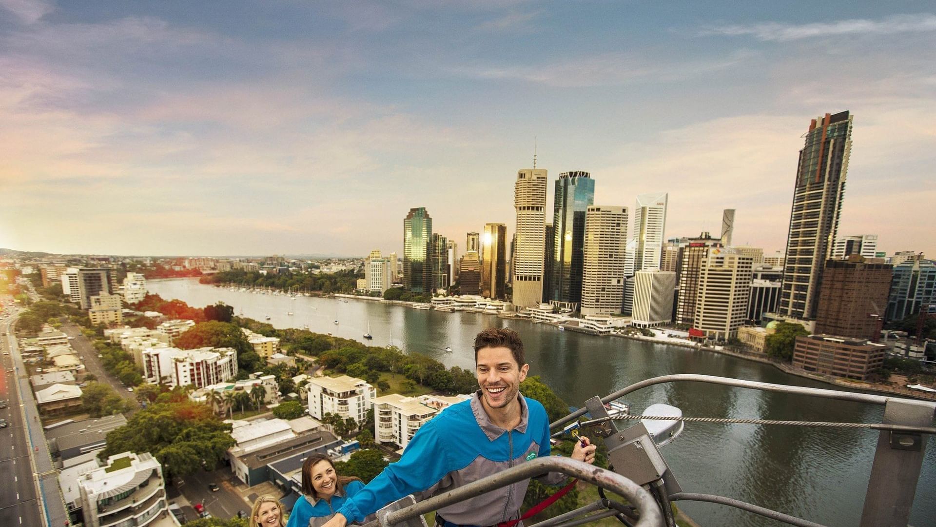 People climbing the Story Bridge with the sunlit Brisbane city skyline and river in the background near The Sebel Brisbane