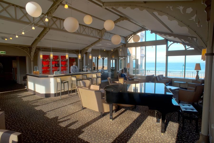Grand piano in a stylish hotel lounge bar with large windows overlooking the ocean at Le Grand Hôtel des Thermes
