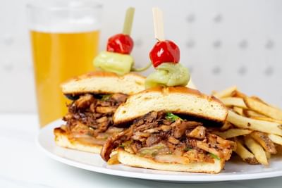 Close-up of sandwich served on a white plate with a glass of beer at Stein Eriksen Residences