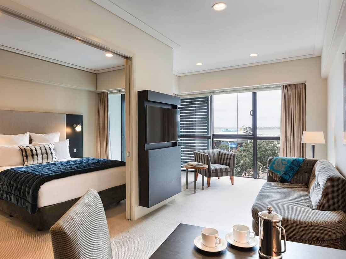 TV lounge with dining area and adjacent bed in Marina View One Bedroom Suite at The Sebel Auckland Viaduct Harbour