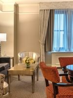 Elegant Premier City View Suite living area with sofa and dining table near the window at Warwick New York