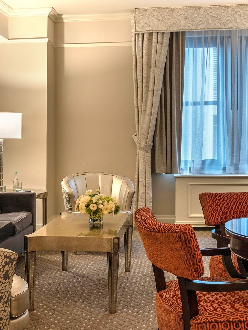 Elegant Premier City View Suite living area with sofa and dining table near the window at Warwick New York