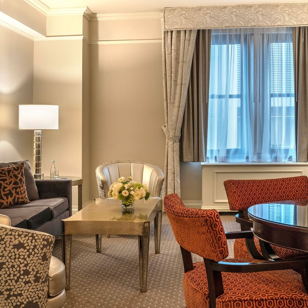 Elegant Premier City View Suite living area with sofa and dining table near the window at Warwick New York