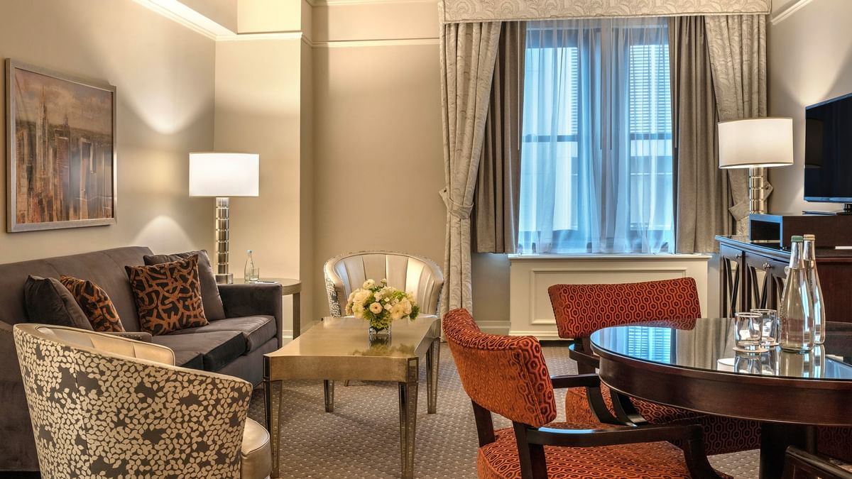 Elegant Premier City View Suite living area with sofa and dining table near the window at Warwick New York