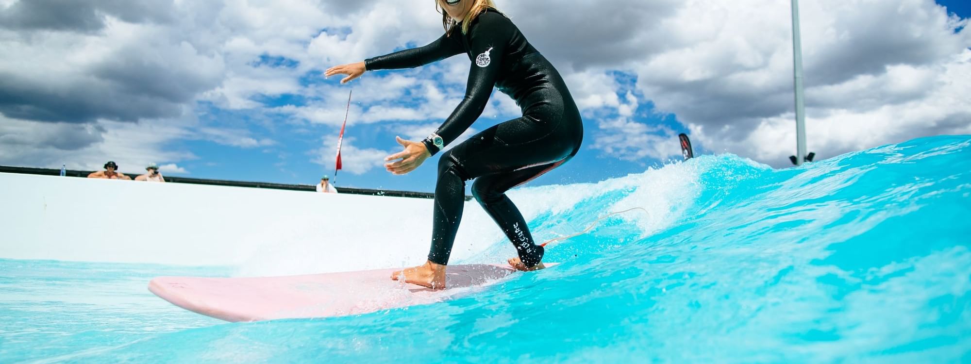 Surfer riding a surfboard on a vibrant blue wave at URBNSURF Sydney near Novotel Sydney Olympic Park