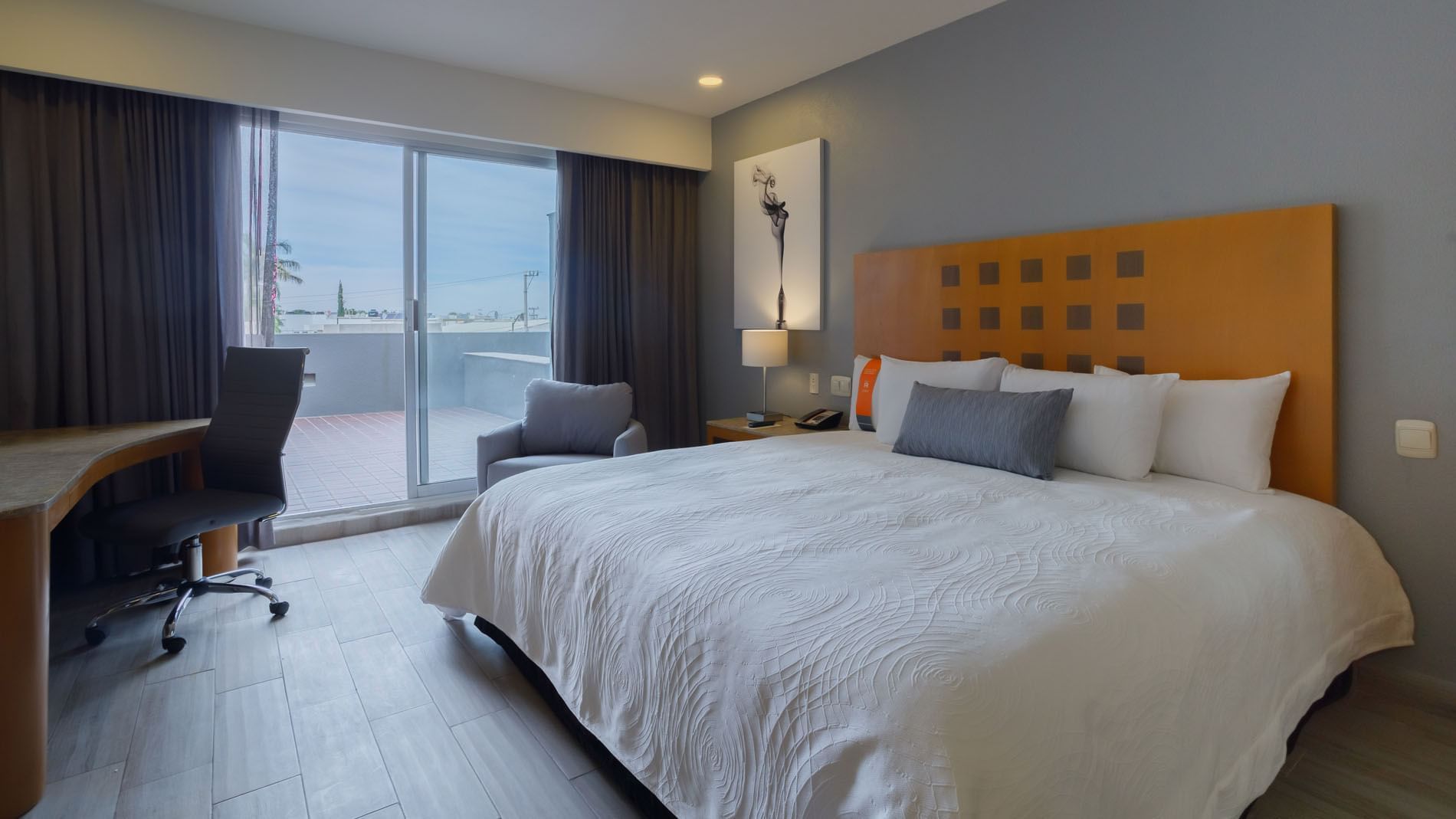 King Deluxe Superior room with a balcony view, light wood floors, and a comfortable working desk at Real Inn Torreon