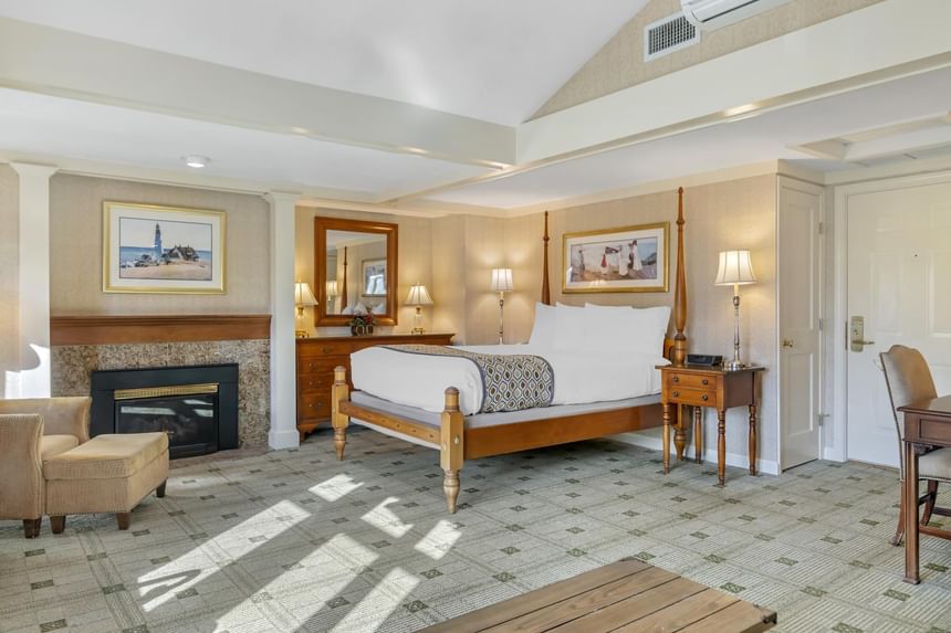 King bed with a wooden stove and comfy chair at Ogunquit Collection