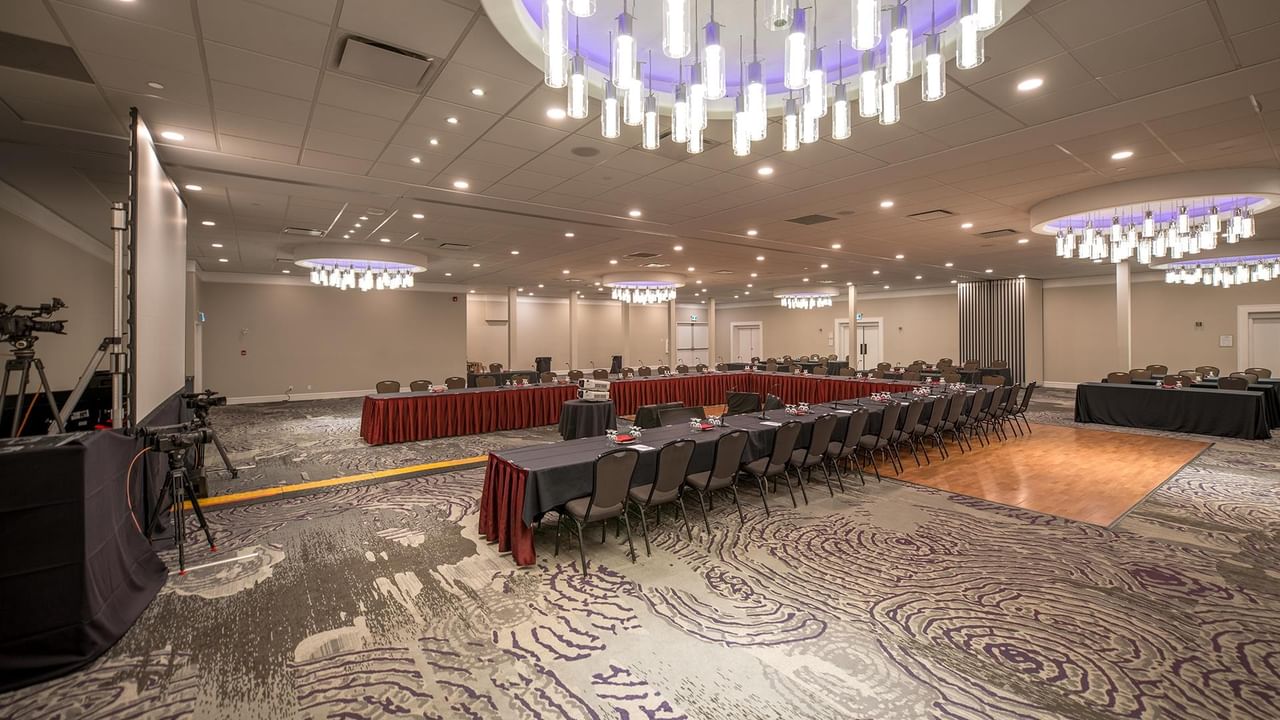 Large conference room with multiple tables, chairs, and chandeliers at Coast Nisku Inn & Conference Centre.