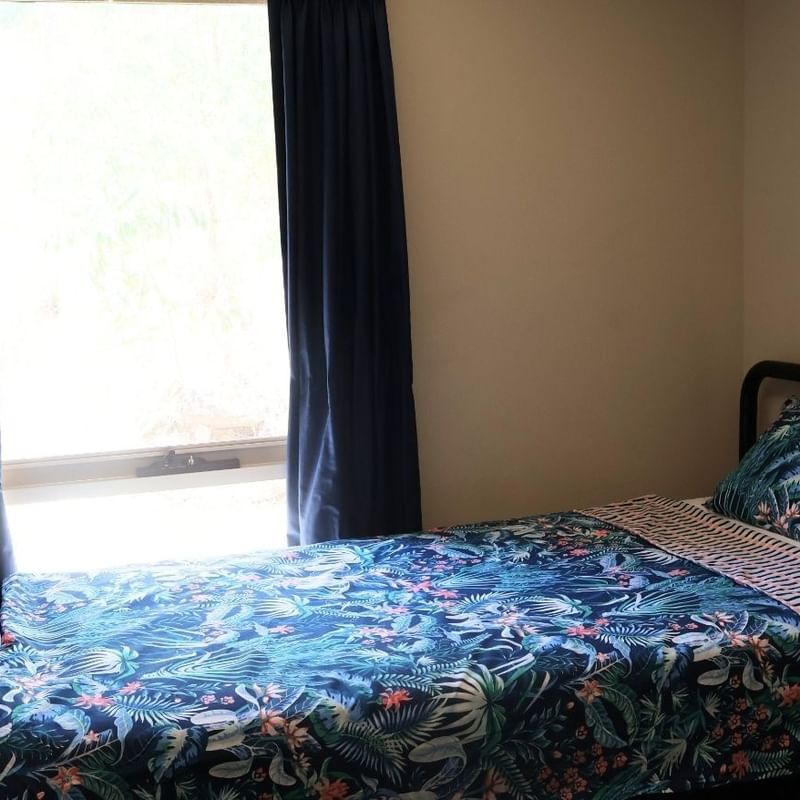 Bedroom with a bed and blue floral bedding at La Trobe University - Villas.