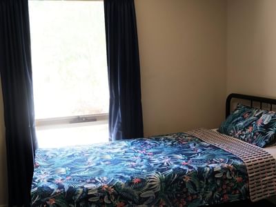 Bedroom with a bed and blue floral bedding at La Trobe University - Villas.