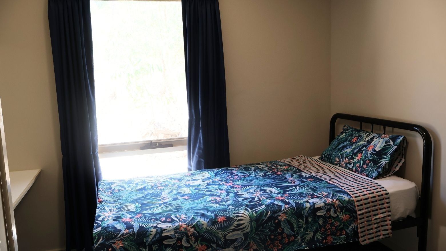 Bedroom with a bed and blue floral bedding at La Trobe University - Villas.