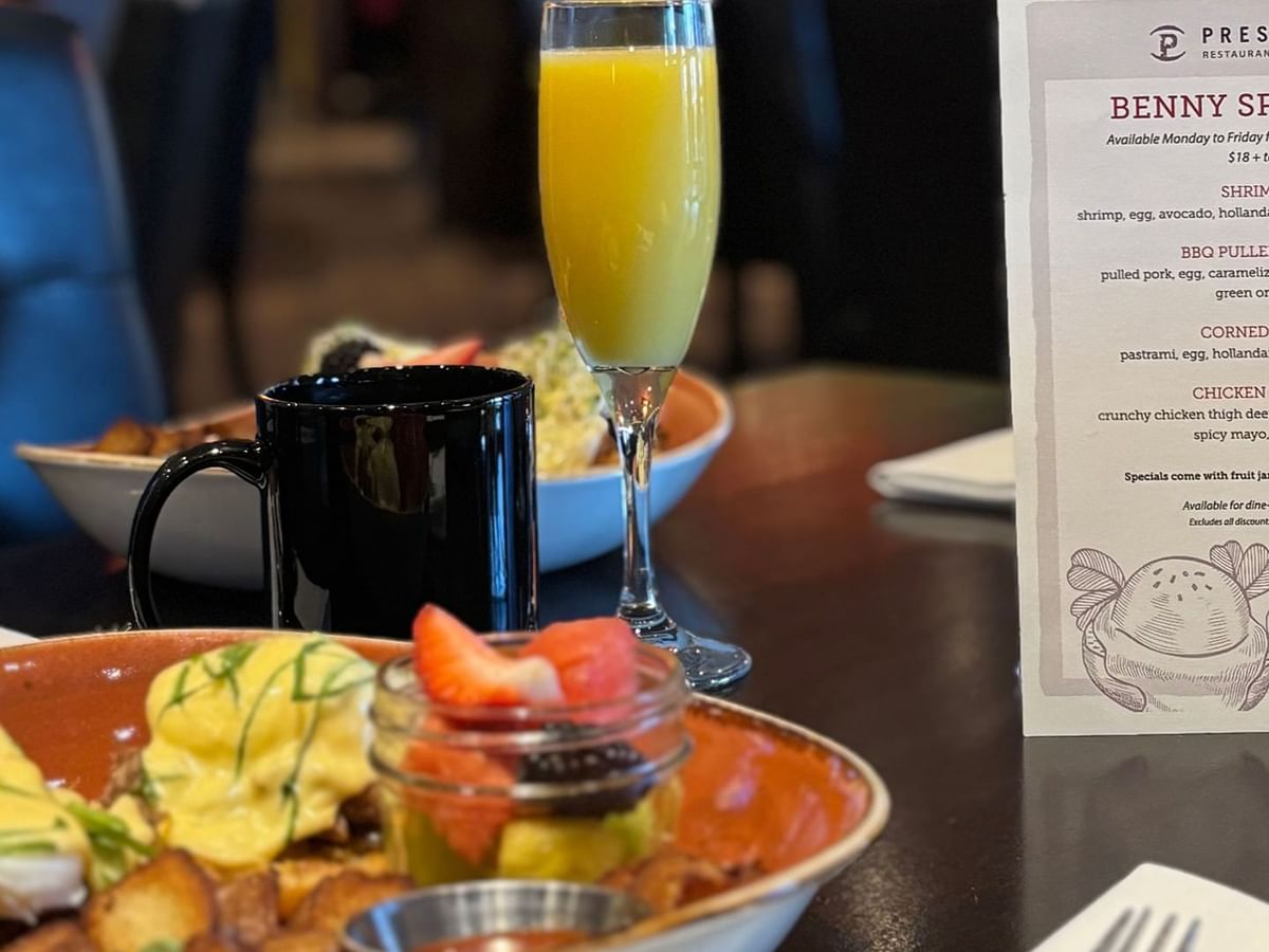 A table with food and drink, including a plate of eggs, orange juice, and a menu.
