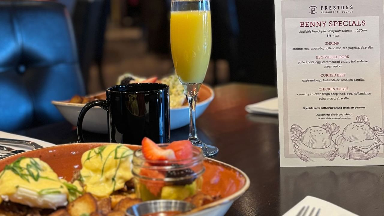 A table with food and drink, including a plate of eggs, orange juice, and a menu.