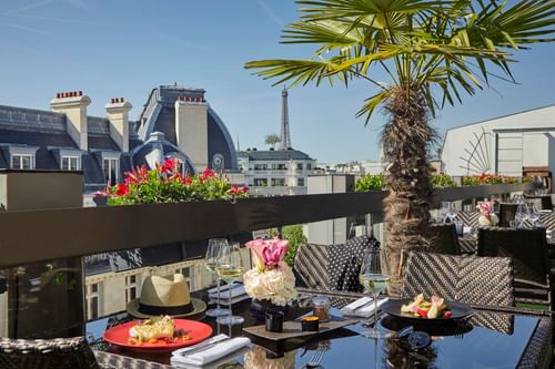 Terrasse offrant une vue sur la tour Eiffel avec plats et boisso