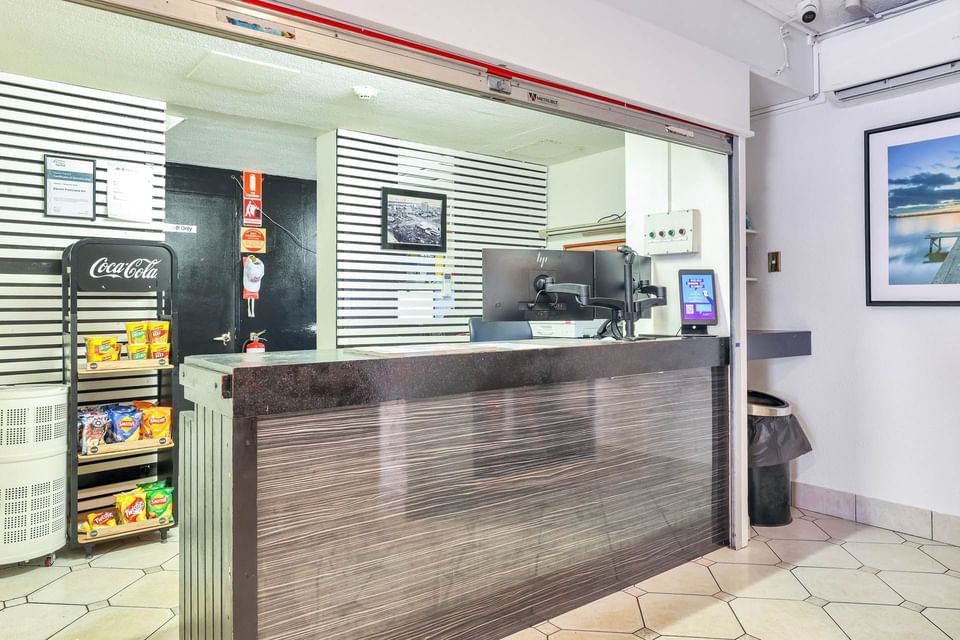 Reception desk with a computer and snacks rack at Darwin Poinciana Inn